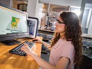 Photo of a student wearing safety goggles working on a computer Photo of a student wearing safety goggles working on a computer